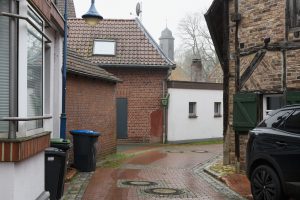 Historic alley in Schermbeck with red brick walls, cobblestones, and half-timbered houses.