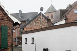 Old and modern buildings in Schermbeck with a church tower in the background, typical of the cityscape.