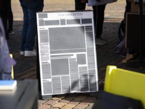 Ein Schild mit einer abstrahierten Zeitungsgestaltung mit wenig Text.