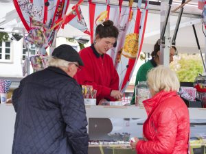 Artist Lisa Klosterkötter serves two older customers at a market stall selling sweets, the Snail Kiosk.