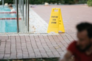Yellow sign reading “Do not talk to the artwork” by Cem A. placed by the poolside.