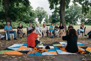 Gesprächsrunde auf Picknickdecken und Stühlen im Parkbereich des Solebads, mit Meral Kureyshi.