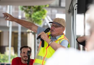 Ein Teilnehmer der Gesprächsrunde erzählt mit Mikrofon und ausgestrecktem Arm von seinen Erinnerungen an das ehemalige City-Hochhaus.