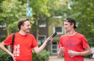 Kurator Julian Rauter führt ein Gespräch mit einem Besucher und hält ihm dabei ein Mikrofon hin.