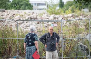 Vor dem abgesperrten Abrissgelände des ehemaligen Wohnturms stehen zwei Personen im Gespräch; einer von ihnen ist der Fotograf Jochen Lempert.