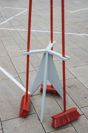 Close-up of a wooden stand holding several red brooms used for the “slalom sweeping” discipline at the Hammer Caretaker Championships.