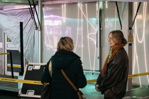 Zwei Personen unterhalten sich vor dem offenen Tour-Trailer.