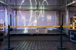 Der geöffnete Tour-Trailer zeigt die Laserinstallation „spin jump crawl climb dream bite hunt“ von Paul Spengemann, abgesperrt mit gelbem Band von Cem A.