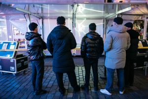 Eine Gruppe von Menschen steht vor dem offenen Trailer und betrachtet die Laserinstallation „spin jump crawl climb dream bite hunt“ von Paul Spengemann.