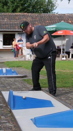 Minigolf Europameister Sebastian Heine schlägt einen Minifgolf auf einer Bahn mit blauen Hindernissen.